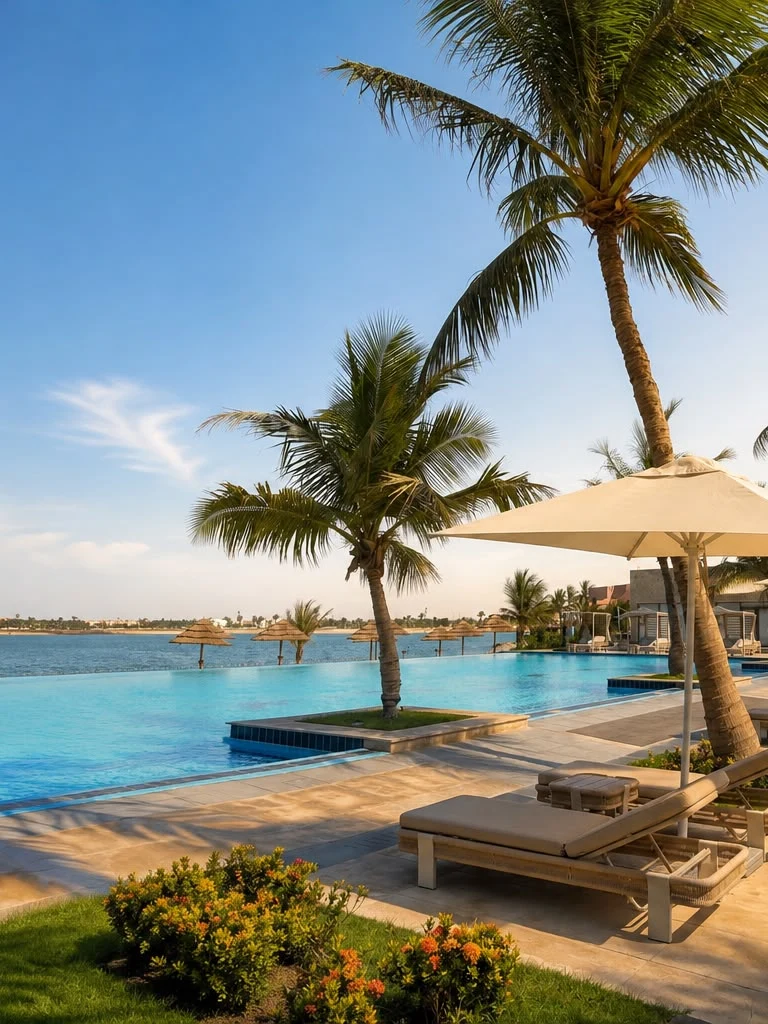 Sariya’s infinity pool beside the Red Sea, with palm trees, loungers and parasols in the late-afternoon sun
